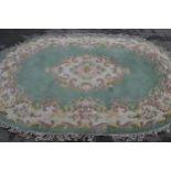 Indian oval floral pattern rug with a central medallion and floral border on a green ground, 9ft x