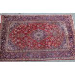 Modern Kashan carpet with a medallion and all-over floral design on a red ground with borders, 9ft