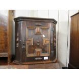 Small oak hanging corner cabinet with a single geometric moulded panel door, 18ins wide