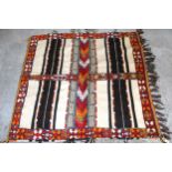 Small part piled rug with a four panel design and tassel border, 4ft 8ins x 4ft 2ins approximately