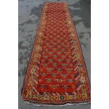 Kazak runner with an all-over stylised flowerhead design on a red ground with borders, 12ft 10ins