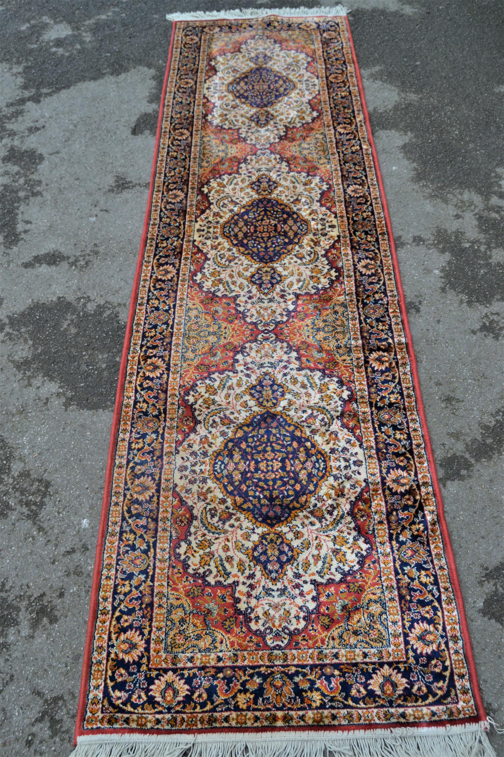 Modern machine woven rug of Persian design with a triple medallion on a rose ground with borders,