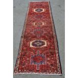 Modern Karaja runner with a seven medallion and all-over floral design on a red ground with narrow