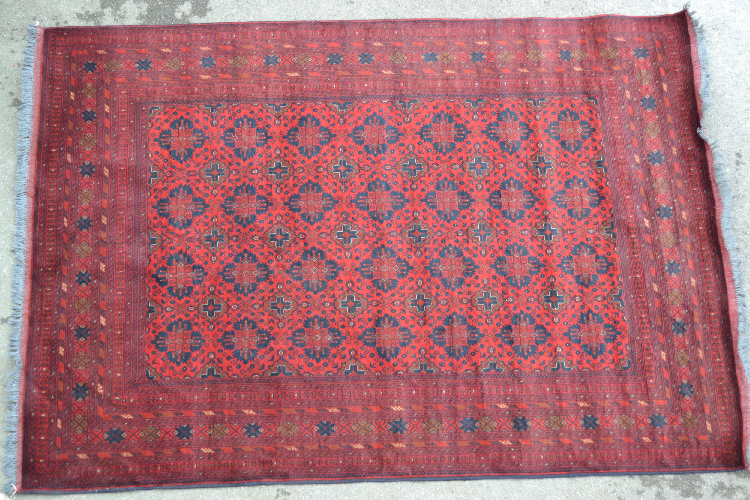 Afghan carpet with four rows of seven gols on a wine ground with multiple borders, 9ft 6ins x 6ft