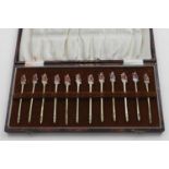 AN ART DECO CASED SET OF TWELVE SILVERGILT COCKTAIL STICKS each enamelled on the terminal in muted