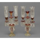 A PAIR OF CUT GLASS THREE BRANCH CANDELABRA, the scrolling glass branches with cranberry glass