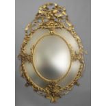 A 19TH CENTURY GILT WALL MIRROR, of oval form with five bevelled plates, surmounted by scrolling