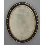 AN IRISH EBONISED AND GILT OVAL WALL MIRROR, 19th century, the frame inset with cut glass studs,