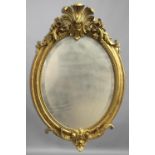 A 19TH CENTURY GILT WALL MIRROR, of oval form, the bevelled mirror plate surmounted by an