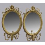 A PAIR OF VICTORIAN GILT GIRANDOLE MIRRORS, the oval plate with foliate and stiff leaf border,