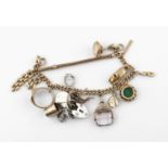 A 15CT GOLD CURB LINK BRACELET each link marked for 15ct gold, suspending assorted charms, including