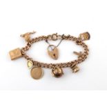 A 9CT GOLD CURB LINK BRACELET with padlock clasp and suspending assorted gold charms, including a