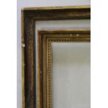 TWO GILTWOOD PICTURE FRAMES one with floral decoration to the frieze corners, the other with bead-
