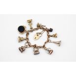 A 9CT GOLD FANCY LINK BRACELET with padlock clasp and suspending assorted gold and hardstone charms,