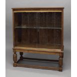 AN INLAID OAK BOOKCASE, dated 1925 with geometric inlay to the frieze, glass sliding doors and