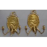 A PAIR OF GILT THREE BRANCH WALL SCONCES, with ribbon surmounts above oval plates embossed with