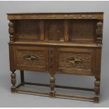 AN INLAID OAK COURT CUPBOARD, the carved scrolling frieze above two cupboards dated 1926 and