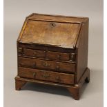 A MINIATURE OAK BUREAU, 18th century, the moulded fall-front enclosing a fitted interior, above