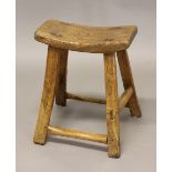 A 19TH CENTURY PROVINCIAL ELM STOOL, the curved seat on splayed legs, height 50cm