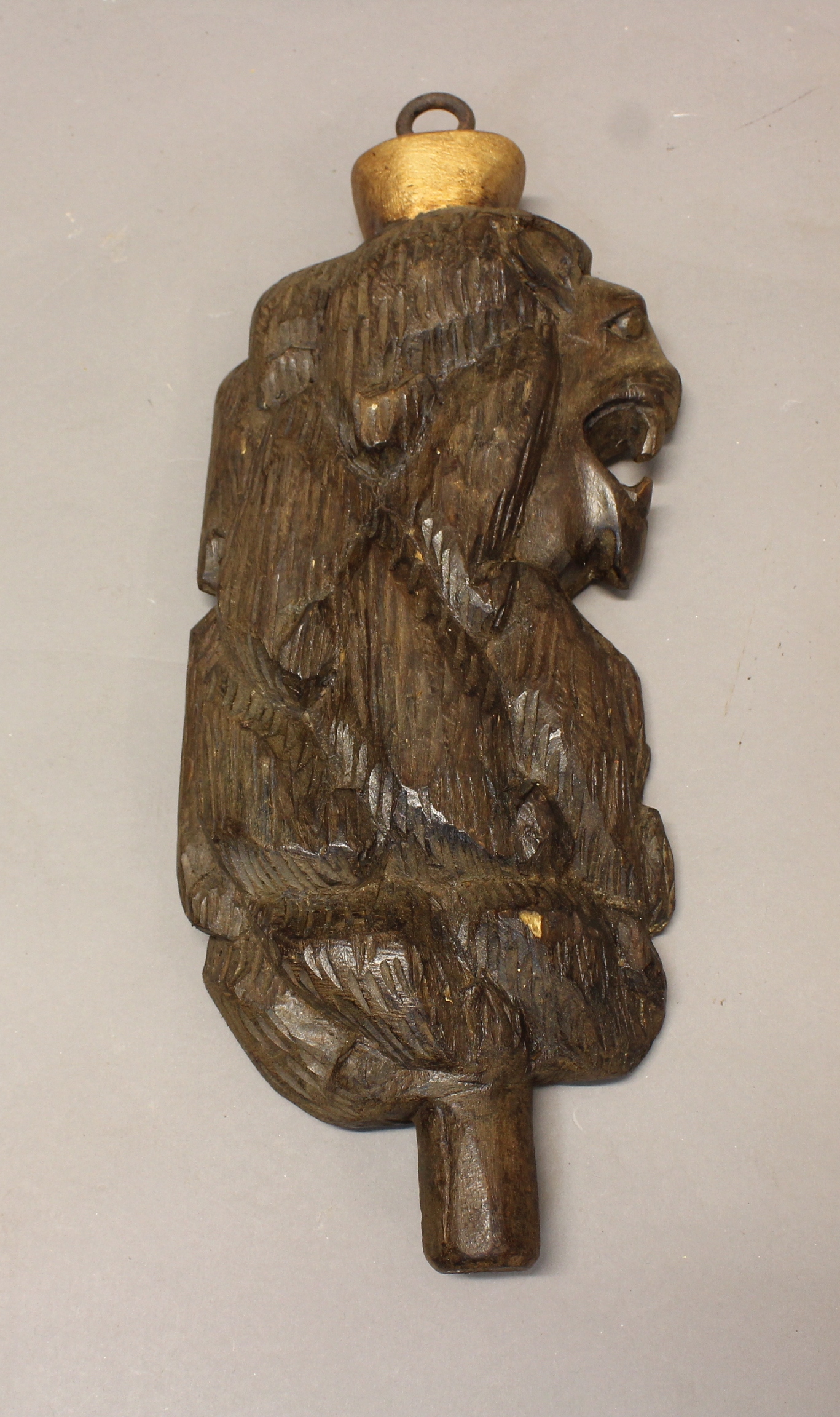 A CARVED OAK LION'S HEAD, with gilt surmount and hanging loop, the reverse with a lead 'PORT'
