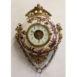 A CONTINENTAL ART POTTERY AND GILT METAL MOUNTED WALL CLOCK, the 5 1/2" cream dial with Arabic