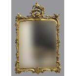 A FLORENTINE STYLE GILT WALL MIRROR, the rounded rectangular plate beneath a Rococo style