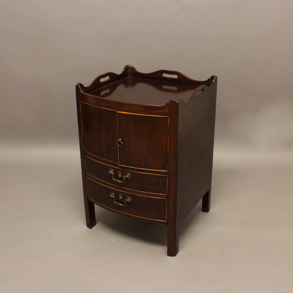 A GEORGE III MAHOGANY BOW FRONT COMMODE. the galleried top above cupboards and a converted drawer,