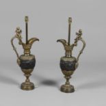 A PAIR OF BRONZE MOUNTED TABLE LAMPS. in the form of ewers, with gilt cherub surmounts and bands