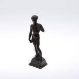 AFTER MICHELANGELO (1475-1564). A patinated bronze study of David, on a naturalistic outswept base