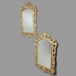 A PAIR OF GILTWOOD WALL MIRRORS. early 20th century, the arched rectangular plates in a scrolling