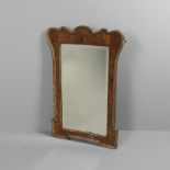 AN 18TH CENTURY WALNUT AND PARCEL GILT WALL MIRROR. of shaped rectangular form, with bevelled mirror