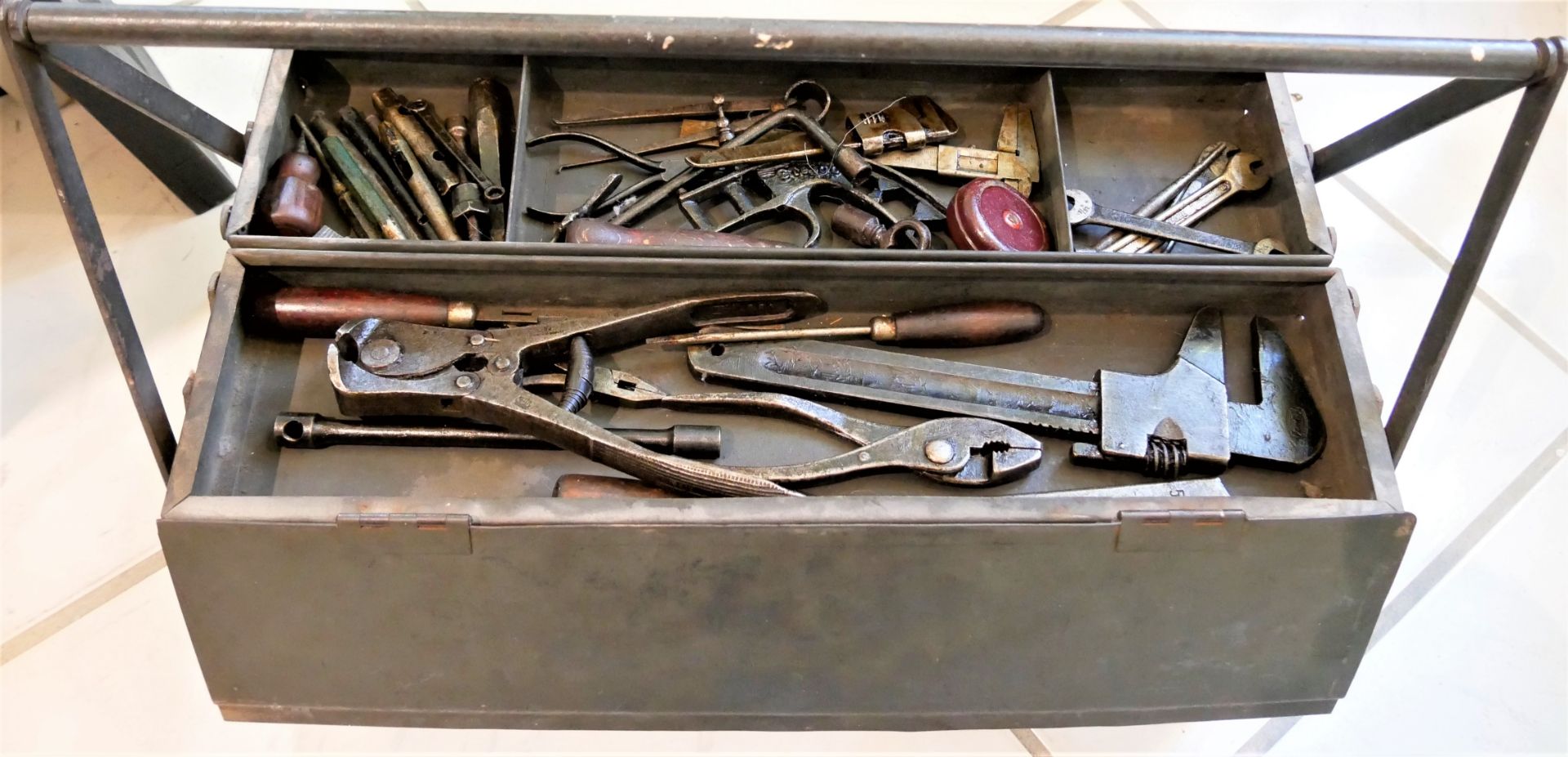 alter Werkzeugkasten gefüllt mit Werkzeugen. Verschiedene Teile, dabei Zangen, Schraubenzieher, etc.