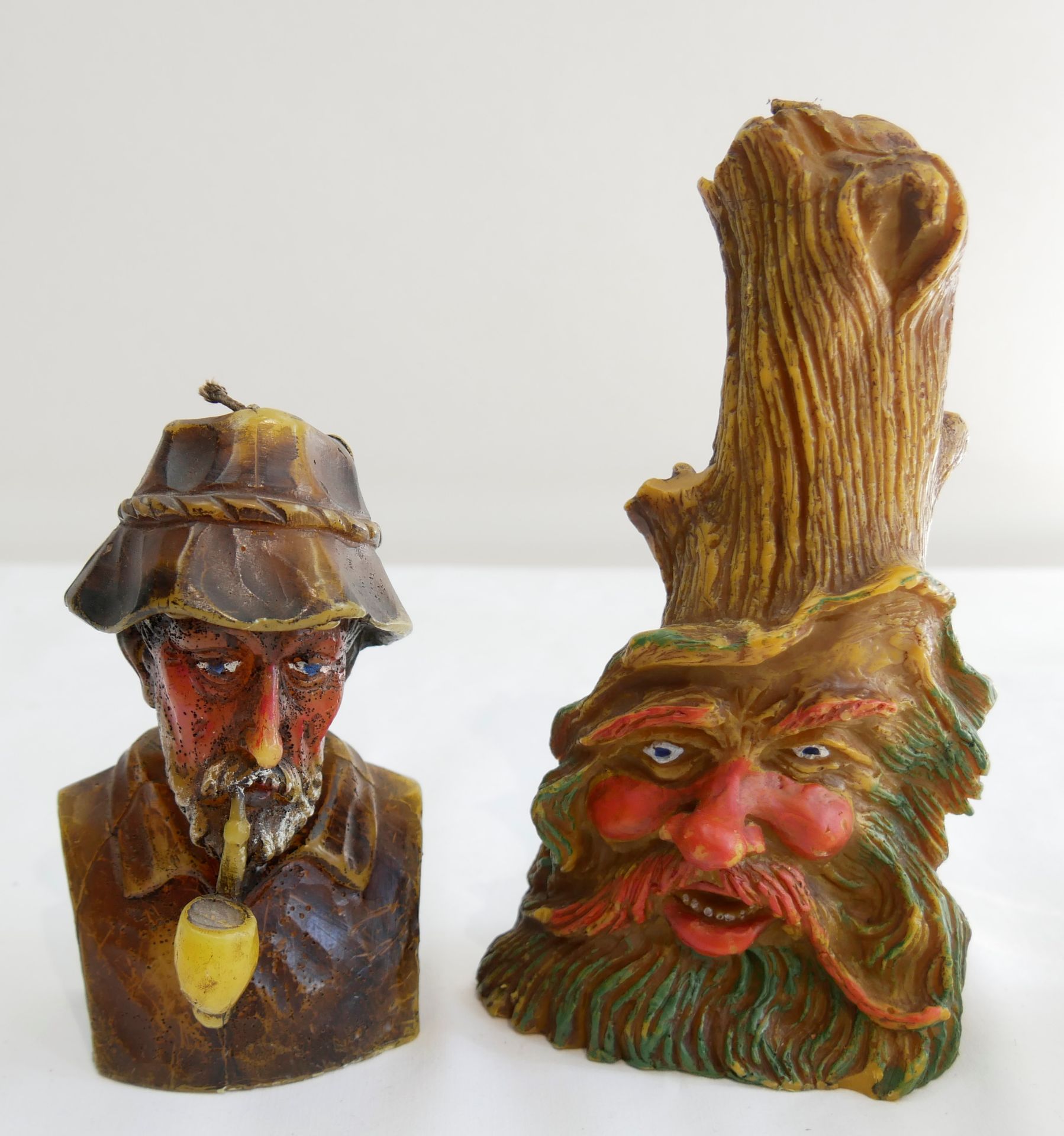 2 Wachsfiguren "Mann mit Pfeife", 1x Höhe ca. 15,5 cm, Gesicht in Baum, 1x Höhe ca. 21 cm