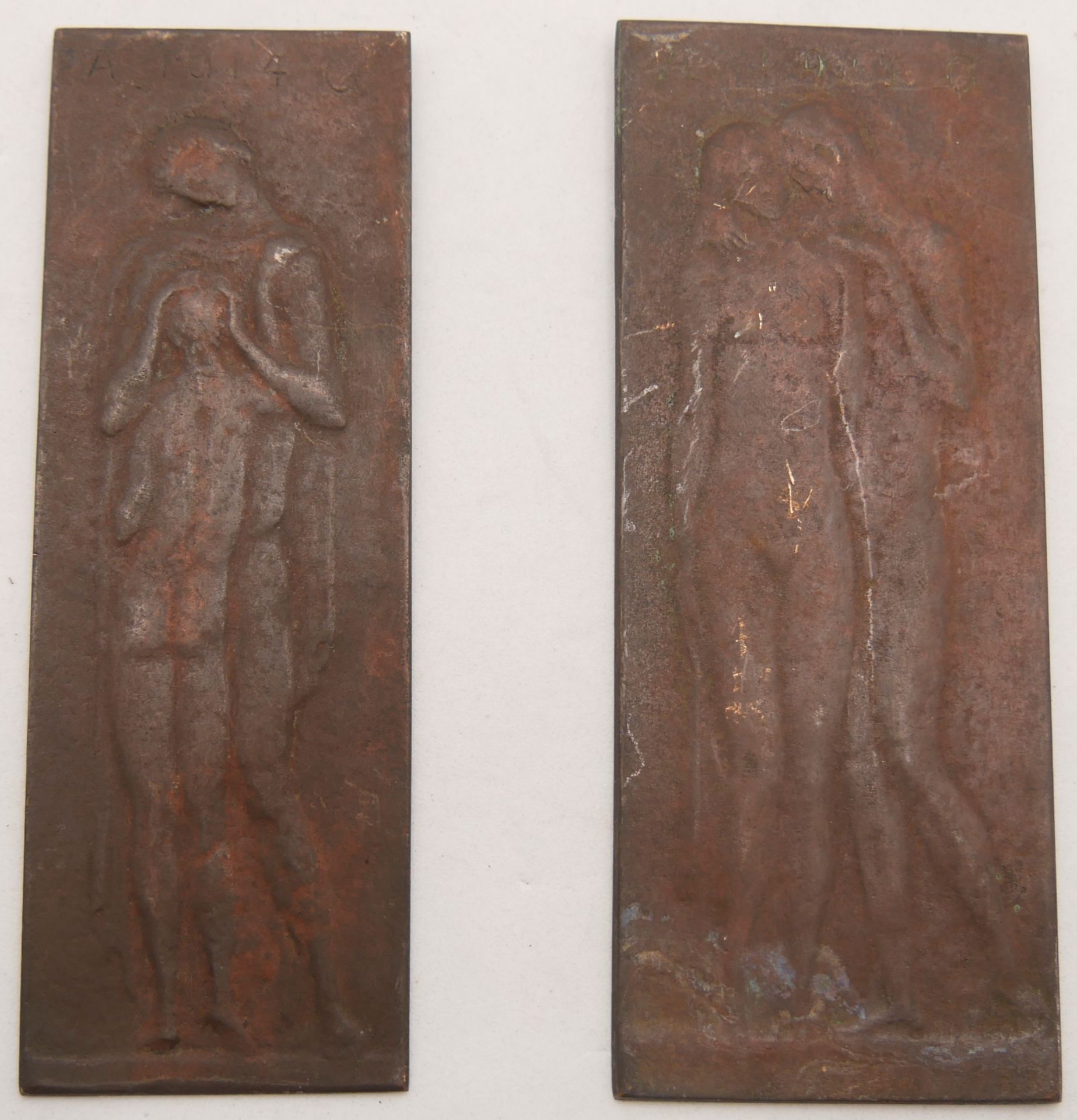 2 Metallreliefs AG 1914. 1x Höhe ca. 12 cm, Breite ca. 5 cm. 1x Höhe ca. 11,5 cm, Breite ca. 4 cm