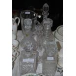 SEVEN CUT CRYSTAL AND GLASS DECANTERS, AND A WATER JUG, THE LARGEST 32CM HIGH.