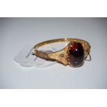 VICTORIAN YELLOW METAL AND GARNET SET HINGED BANGLE, SET WITH OVAL CABOCHON GARNET STAMPED '18C',