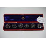 CASED SET OF SIX WHITE METAL CIRCULAR BUTTONS OF PIERCED OPEN SCROLLWORK FORM.