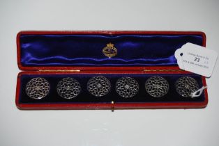 CASED SET OF SIX WHITE METAL CIRCULAR BUTTONS OF PIERCED OPEN SCROLLWORK FORM.