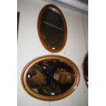 TWO OVAL WALL MIRRORS, ONE WITH OAK FRAME, THE OTHER WITH GOLD PAINTED COMPOSITE FRAME, BOTH WITH