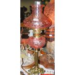 EARLY 20TH CENTURY BRASS AND PINK FLUTED GLASS OIL LAMP, THE BASE WITH ACANTHUS STYLE TRIPOD BASE