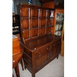 A 20TH CENTURY ERCOL STYLE DARK STAINED DRESSER WITH THREE TIER PLATE RACK OVER A BASE WITH TWO