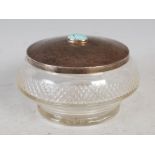 An Arts & Crafts white metal mounted cut glass circular powder jar and cover, the hammered cover set