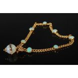 A yellow metal and opal bracelet, the chain set with seven opal cabochons and suspending an opal
