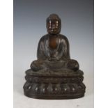 A Chinese bronze figure of a buddha, seated on a double lotus base cross-legged, meditating, wearing