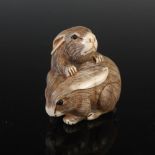 A Japanese carved ivory netsuke, probably Meiji Period, depicting two rabbits, two character