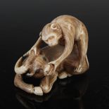 A Japanese carved ivory netsuke, probably Meiji Period, depicting a macaque on top of a recumbent
