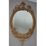 A 19th century gilt wood girandole, the oval frame with scroll pediment and two candle sconce
