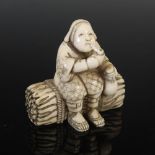 A Japanese carved ivory netsuke, probably Meiji Period, depicting a woman seated on a bundle of