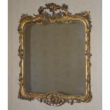 A 19th century gilt wood Rococo style wall mirror, the scroll and foliate carved frame with ribbon