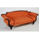 An early 19th century rosewood sofa, with a low upholstered back and outswept arms with acanthus